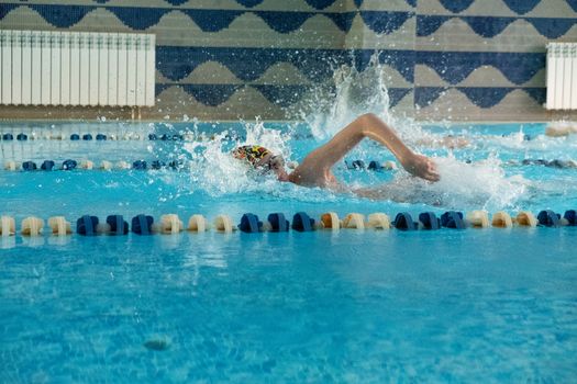 Children swimming freestyle. Indoor swimming pool with clear blue water.