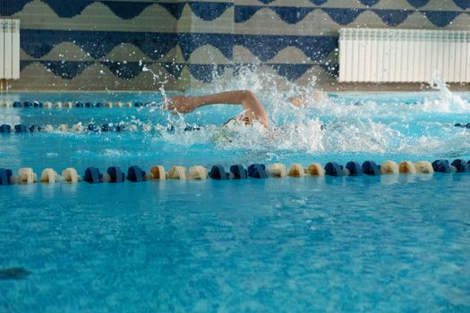 Children swimming freestyle. Indoor swimming pool with clear blue water.