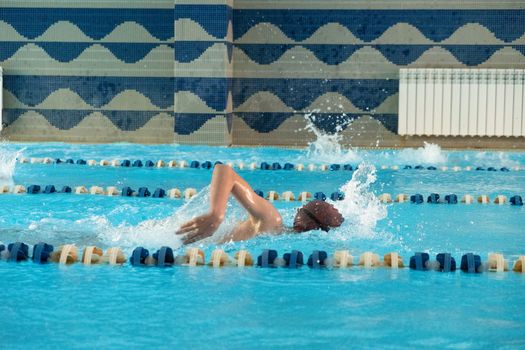 Children swimming freestyle. Indoor swimming pool with clear blue water.