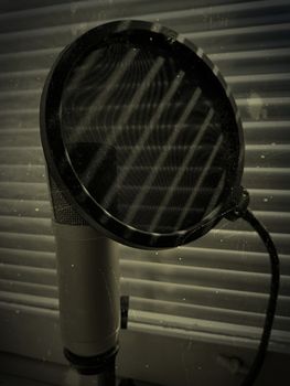 microphone and pop up filter concept grunge photo. blinds shadow falls on him