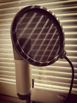 microphone and pop up filter concept grunge photo. blinds shadow falls on him