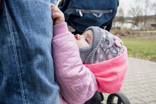 little girl climbs on dad's trousers, beautiful photo of a child who wants to get his hands on