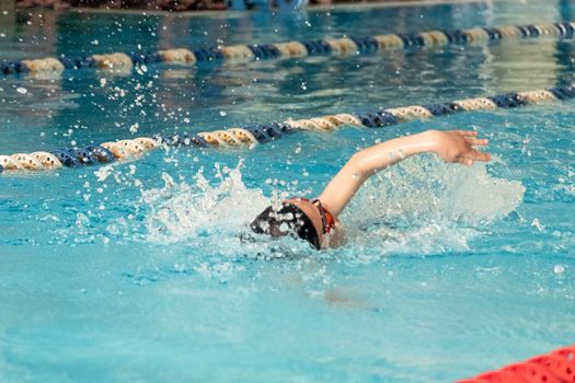 Children swimming freestyle. Indoor swimming pool with clear blue water.