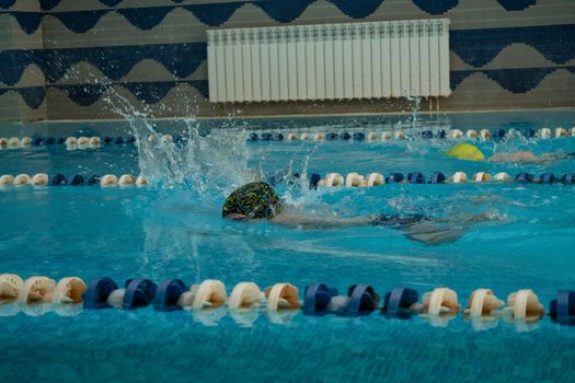 Children swimming freestyle. Indoor swimming pool with clear blue water.