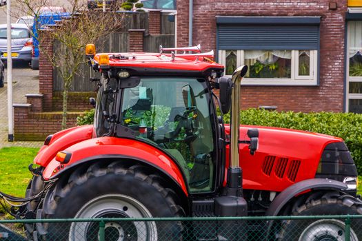 red tractor parked in a residential area, countryside transportation background, peasant visiting a village