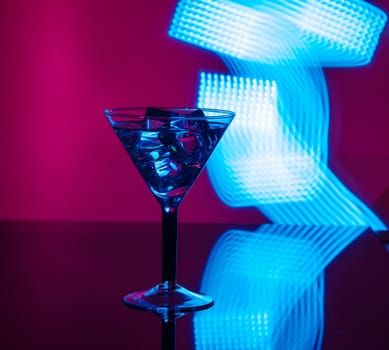 A glass of martini with ice cubes on a club background