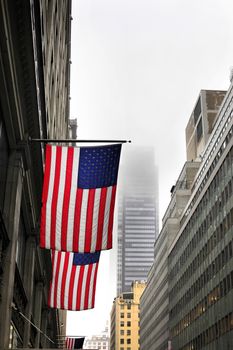 New York, NY, USA - American flags on a pole, fluttering in the wind, on the facade of a building on a foggy day