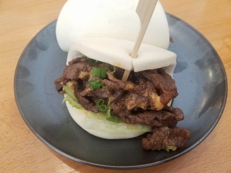 Korean beef with sauce and vegetables in white bread bun