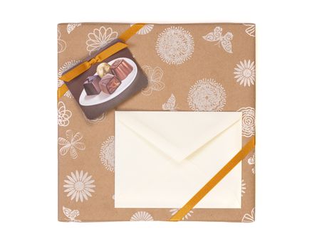 Gift wrapped box with chocolate candies and golden tape on a white background with copy space envelope.