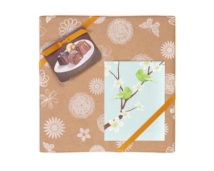 Gift wrapped box with chocolate candies and golden tape on a white background with greeting card.