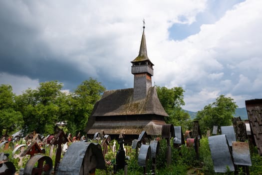 Ieud Hill Church and its graveyard, the oldest wood church in Maramures, Romania under dramatic sky. The Church belongs to a collection of Wooden Churches of Maramures, UNESCO World Heritage Site.