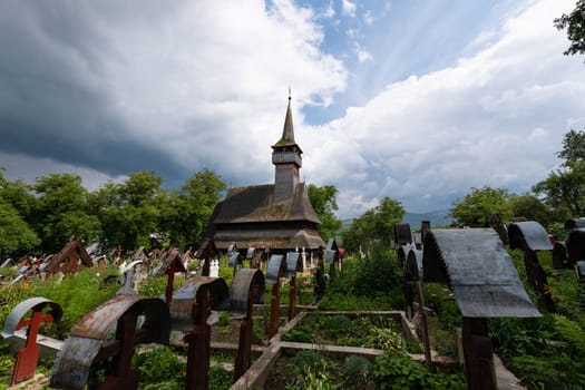 Ieud Hill Church and its graveyard, the oldest wood church in Maramures, Romania under dramatic sky. The Church belongs to a collection of Wooden Churches of Maramures, UNESCO World Heritage Site.