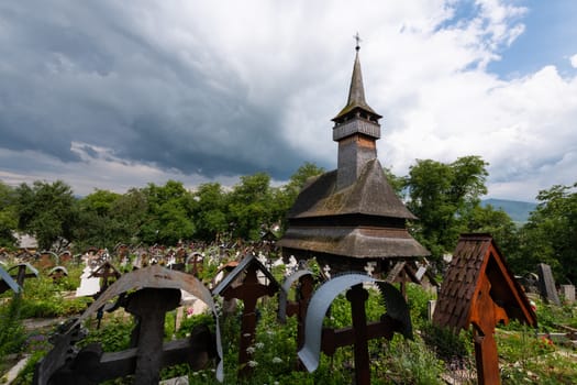 Ieud Hill Church and its graveyard, the oldest wood church in Maramures, Romania under dramatic sky. The Church belongs to a collection of Wooden Churches of Maramures, UNESCO World Heritage Site.