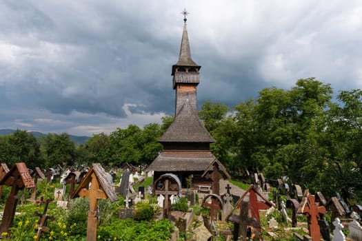 Ieud Hill Church and its graveyard, the oldest wood church in Maramures, Romania under dramatic sky. The Church belongs to a collection of Wooden Churches of Maramures, UNESCO World Heritage Site.