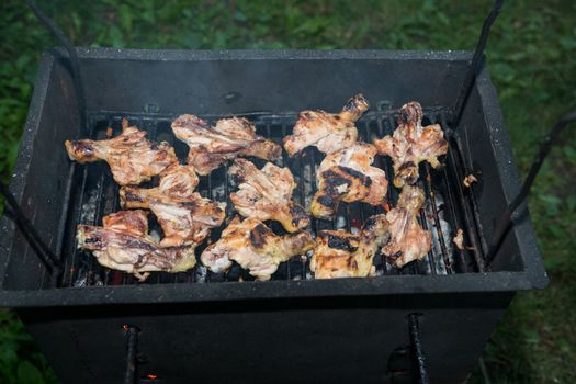 Grilling meats outdoors in a rustic old iron grill an hot coals for family gathering.