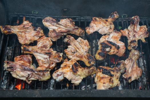 Grilling meats outdoors in a rustic old iron grill an hot coals for family gathering.