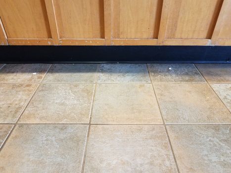 grey or brown stone square tiles and worn brown kitchen cabinet