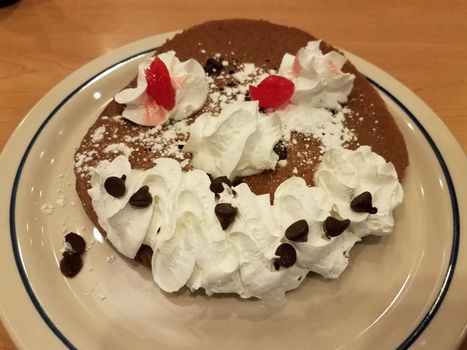 chocolate pancake face with whip cream, cherries, and chocolate