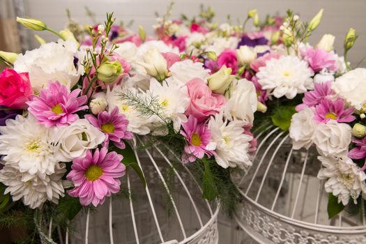 Various bridal flower heads in vintage ornate bird cage as bloom decoration at a wedding reception.