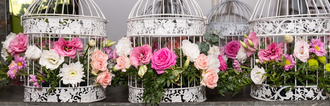 Various bridal flower heads in vintage ornate bird cage as bloom decoration at a wedding reception.