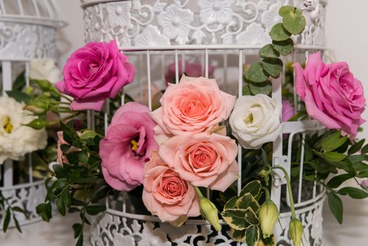 Various bridal flower heads in vintage ornate bird cage as bloom decoration at a wedding reception.