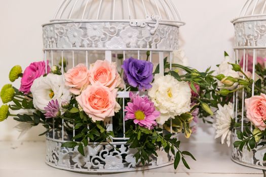 Various bridal flower heads in vintage ornate bird cage as bloom decoration at a wedding reception.