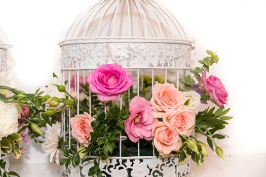 Various bridal flower heads in vintage ornate bird cage as bloom decoration at a wedding reception.