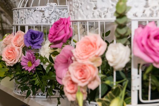 Various bridal flower heads in vintage ornate bird cage as bloom decoration at a wedding reception.