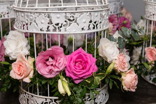 Various bridal flower heads in vintage ornate bird cage as bloom decoration at a wedding reception.