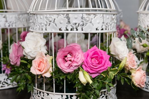 Various bridal flower heads in vintage ornate bird cage as bloom decoration at a wedding reception.