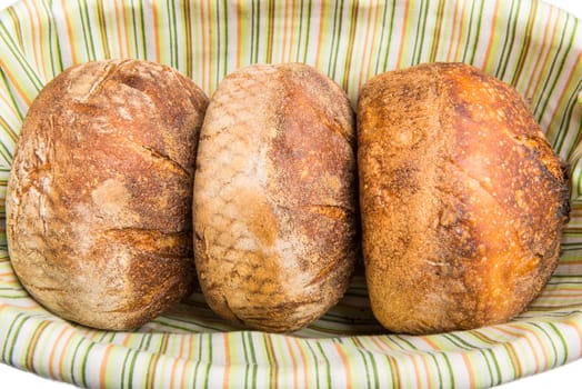 Fresh baked loafs of round artisan sour dough bread in a bread basket.