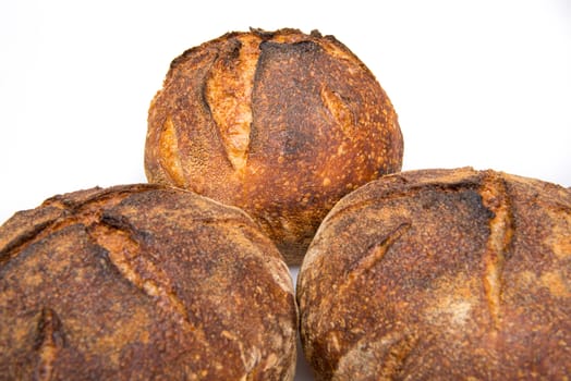 Fresh baked loafs of round artisan sourdough bread isolated on a white background.