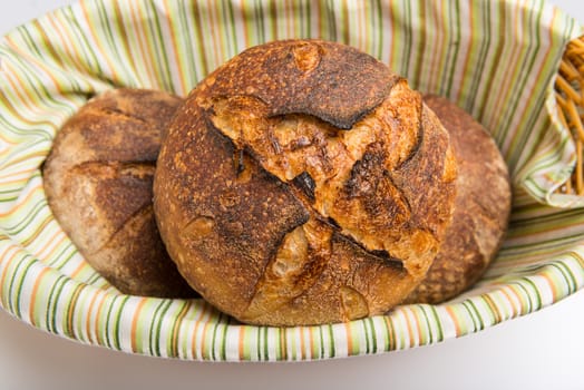 Fresh baked loafs of round artisan sour dough bread in a bread basket.