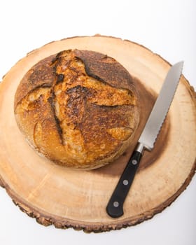 A fresh loaf of round artisan sourdough bread with a breaqd knife.