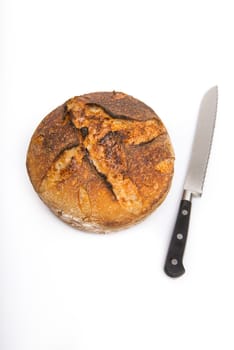 A fresh loaf of round artisan sourdough bread with a breaqd knife.