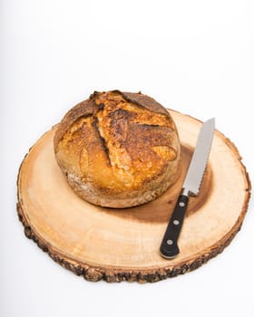 A fresh loaf of round artisan sourdough bread with a breaqd knife.