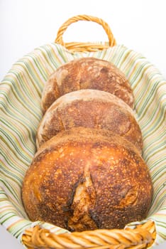 Fresh baked loafs of round artisan sour dough bread in a bread basket.