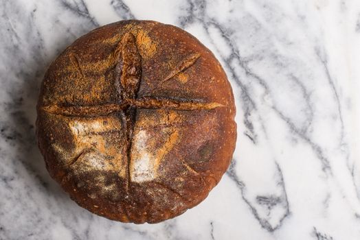 Homemade sourdough bread made in traditional style during Easter or other Christian Holidays with a simple cross signifying that bread is the body of Christ with copy space.