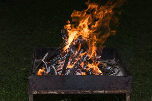 Close-up of blazing fire in BBQ grill at evening.
