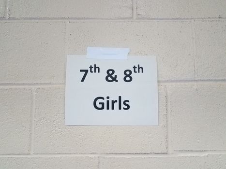 paper 7th and 8th girls sign on white cement or cinder block wall