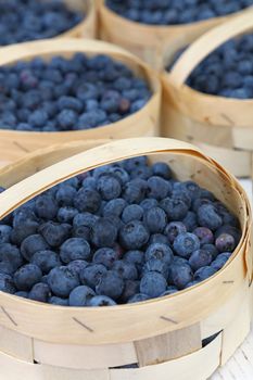 Close up fresh blueberry berries in wooden crate basket container on retail display of farmers market, high angle view