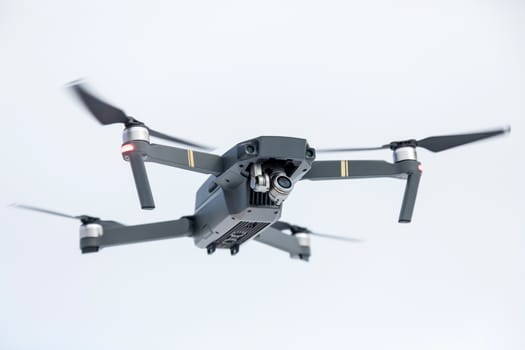 the quadcopter of gray color with the camera in flight against the background of the sky