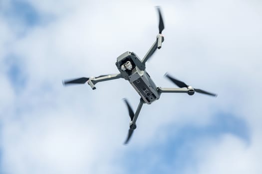 the quadcopter of gray color with the camera in flight against the background of the sky