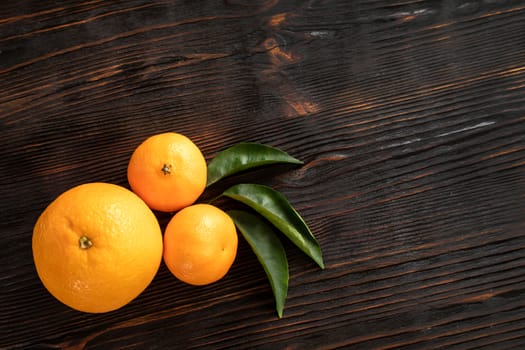 top view of whole ripe tangerines scattered on wooden chopping board