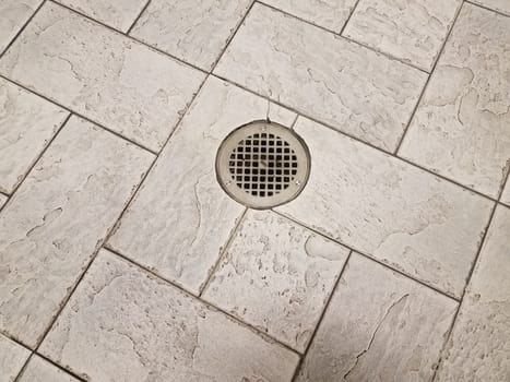 grey rectangle floor tiles with metal drain on ground