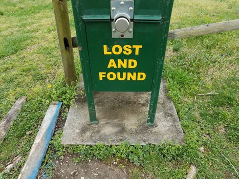 lost and found sign on green metal box with grass