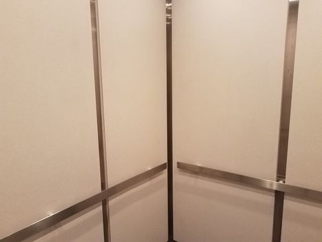 interior of elevator with white walls and metal bars or railing