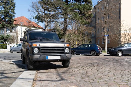 An off-road vehicle is parked on the curb of a German sidewalk. The only mountain such a car can climb in a city.