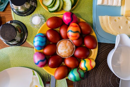 A top view on colored eggs arranged on a plate as a traditional symbol of Easter celebration in Germany together with other toppings.