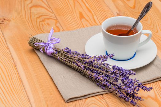 hot tea in a cup with lavender on a linen napkin close-up